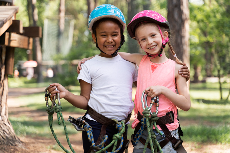 two girls waring helmets and holding their gliding ropes at a party in an amusement park