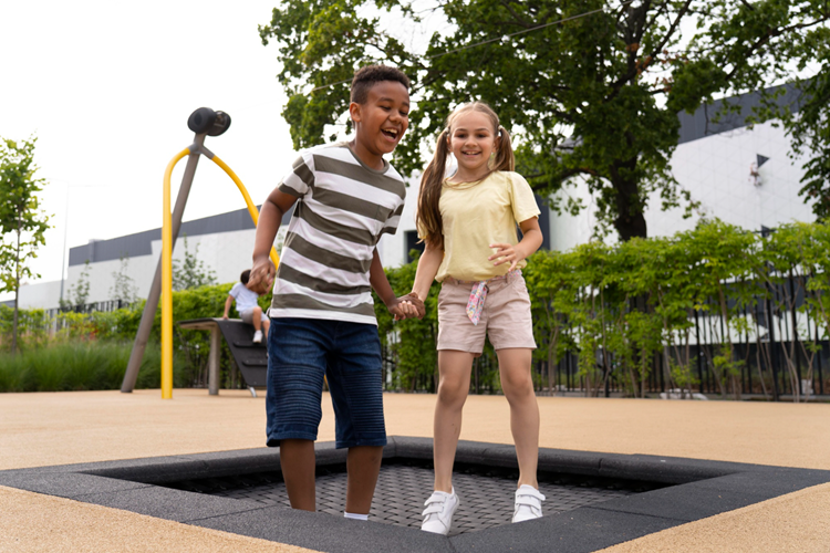 a boy and a girl jumping on a trampoline at a party in a playground