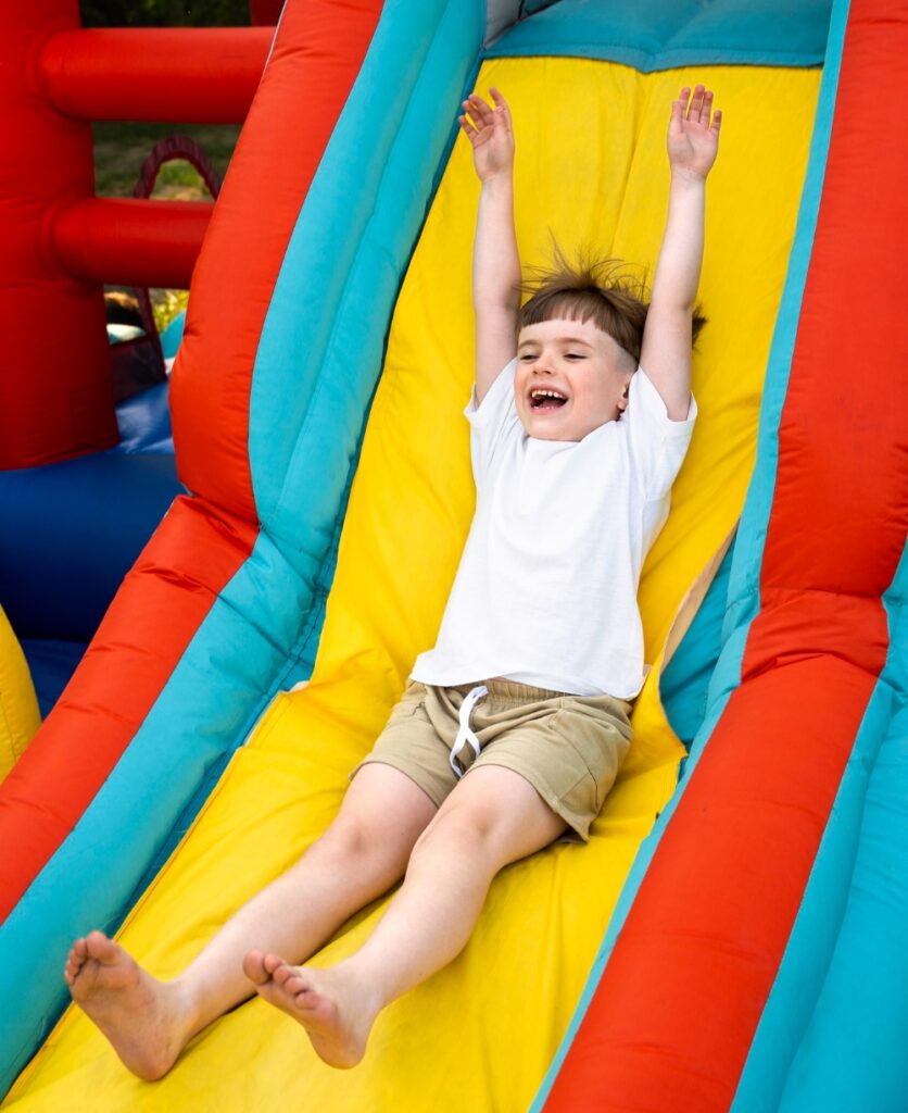 Party-rental-business-insurance. Child sliding down bounce house.